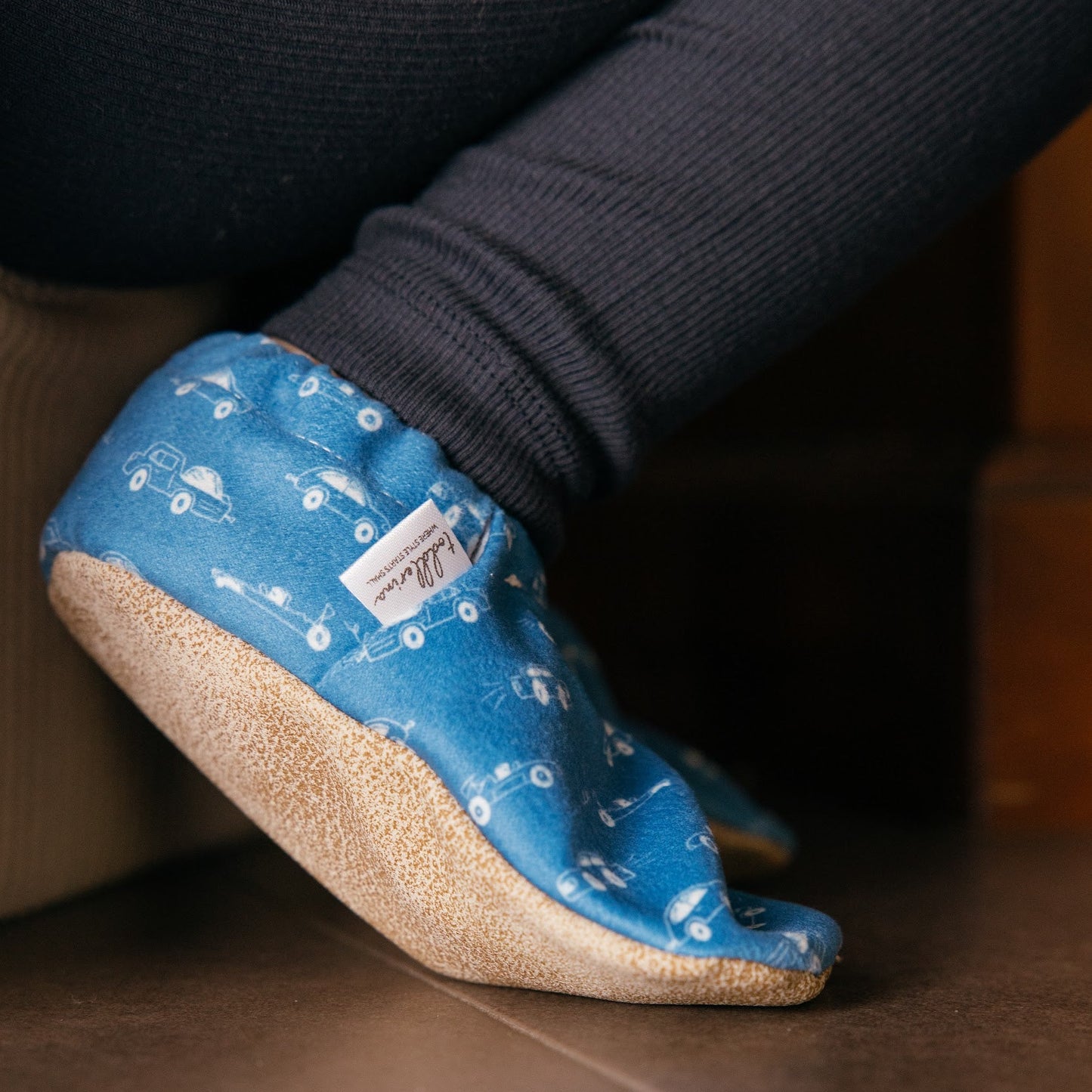 Chaussons pour bébé souples avec un motif amusant de voitures de course sur un tissu bleu marine, parfaits pour les tout-petits et les petits garçons.
