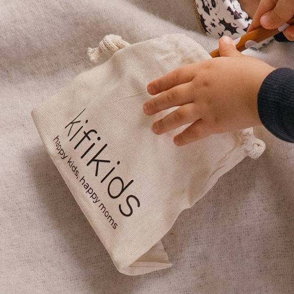 Bébé mettant des jouets dans un sac en coton