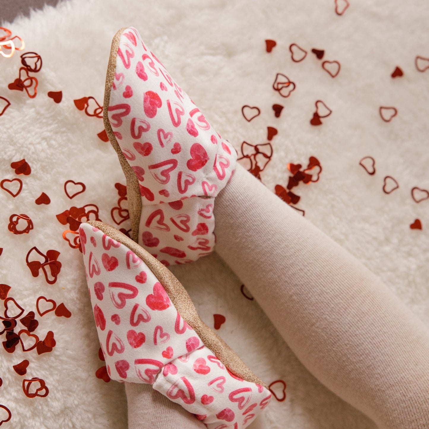 Chaussons bébé avec des cœurs dessinés sur un fond blanc.