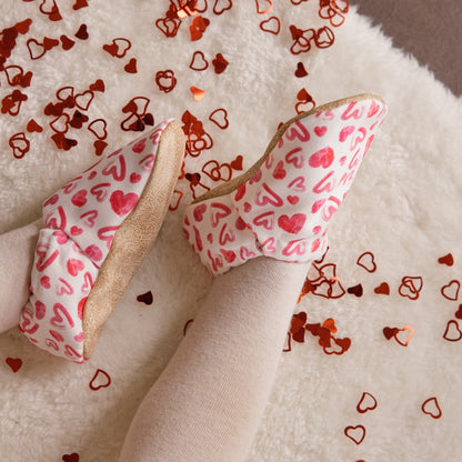 Chaussons bébé avec des cœurs dessinés sur un fond blanc.