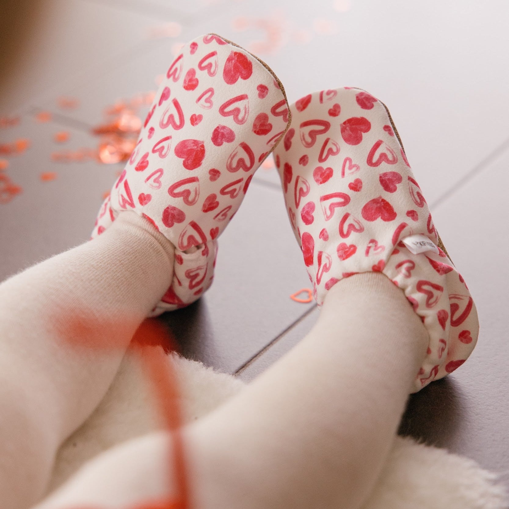 Chaussons bébé avec des cœurs dessinés sur un fond blanc.