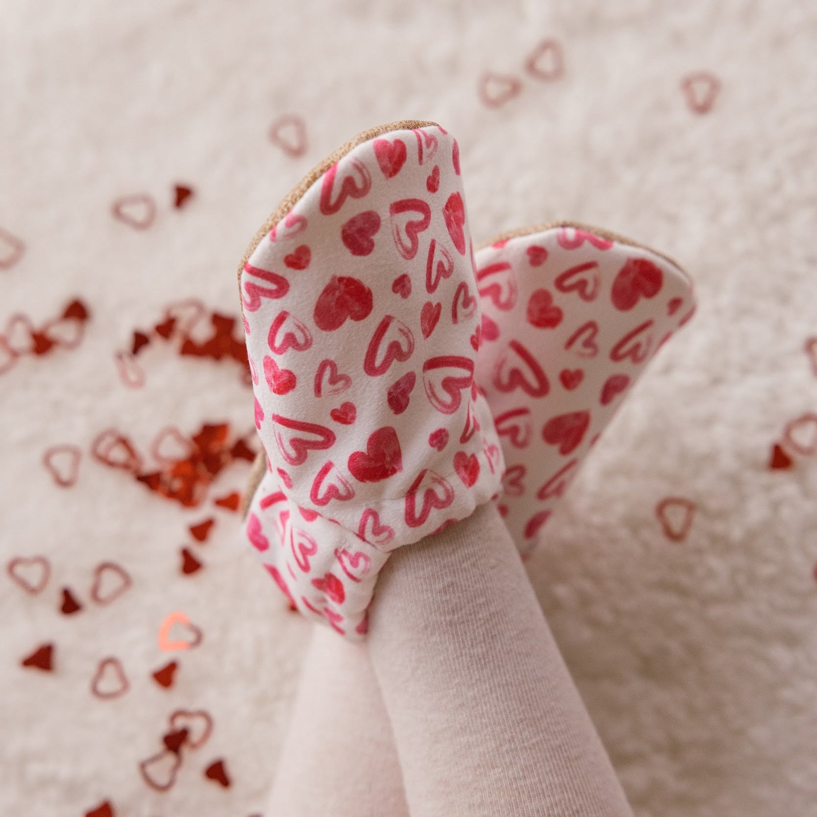 Chaussons bébé avec des cœurs dessinés sur un fond blanc.