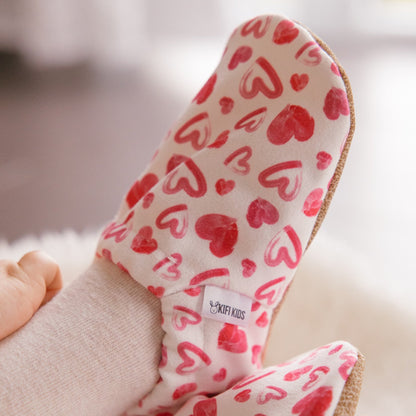 Chaussons bébé avec des cœurs dessinés sur un fond blanc.