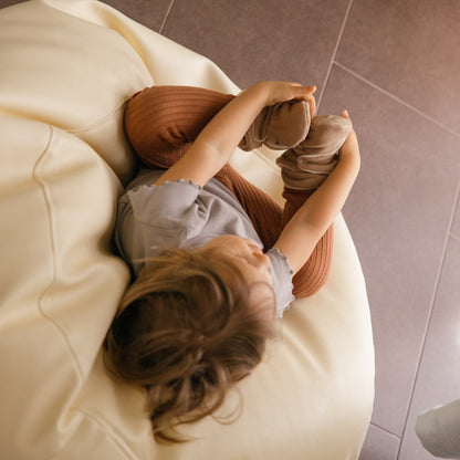 Chaussons en polaire brun latte aux pieds d’un tout-petit.