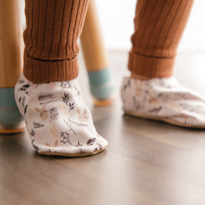 Bébé portant des chaussons à imprimé lapin tout doux, assis sur une chaise.