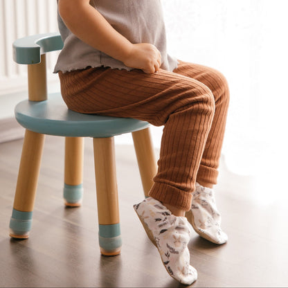 Bébé portant des chaussons à imprimé lapin tout doux, assis sur une chaise.
