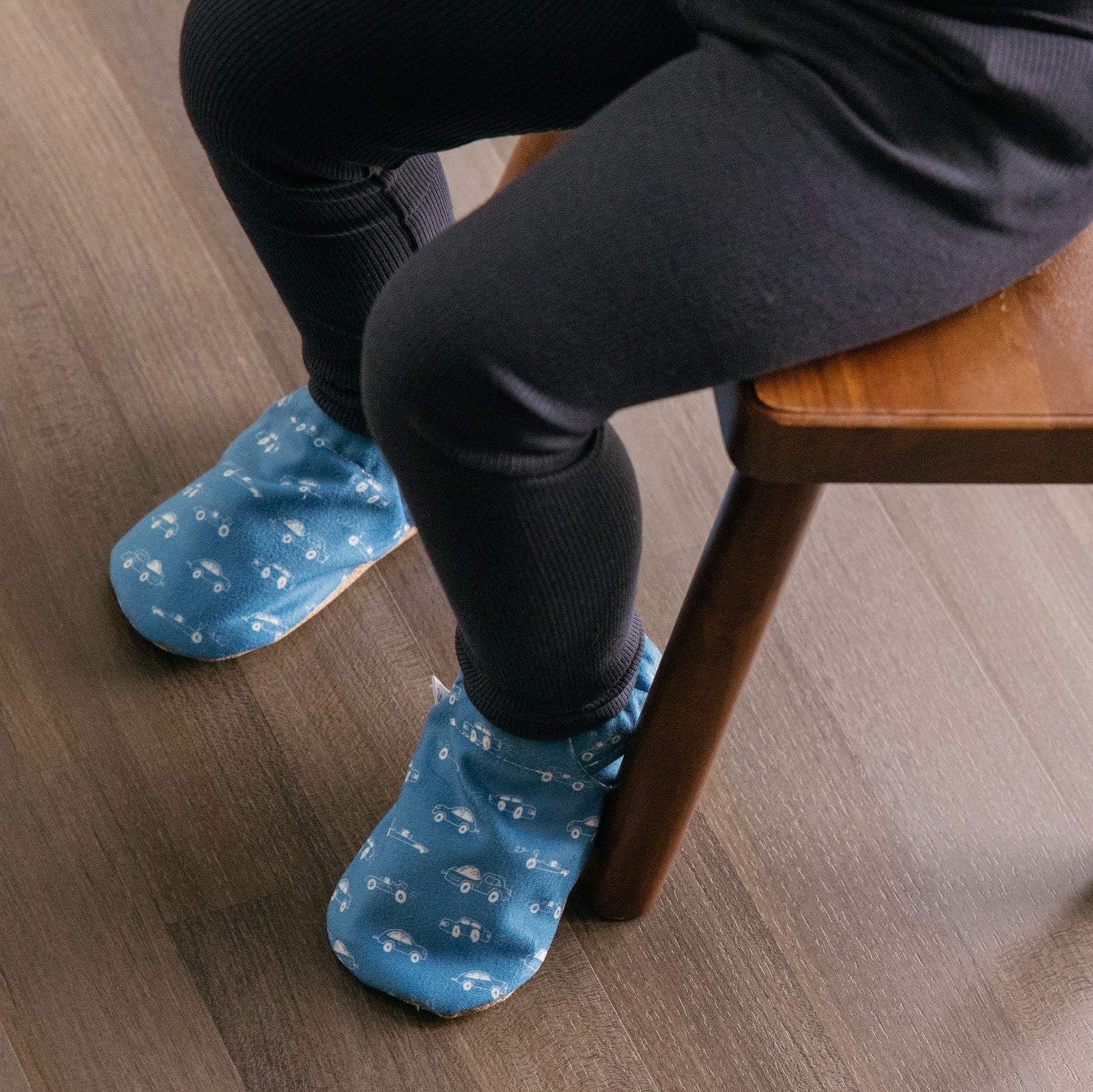 Chaussons pour bébé souples avec un motif amusant de voitures de course sur un tissu bleu marine, parfaits pour les tout-petits et les petits garçons.
