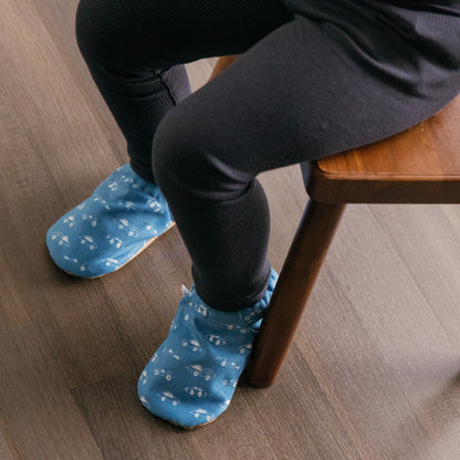 Chaussons pour bébé souples avec un motif amusant de voitures de course sur un tissu bleu marine, parfaits pour les tout-petits et les petits garçons.