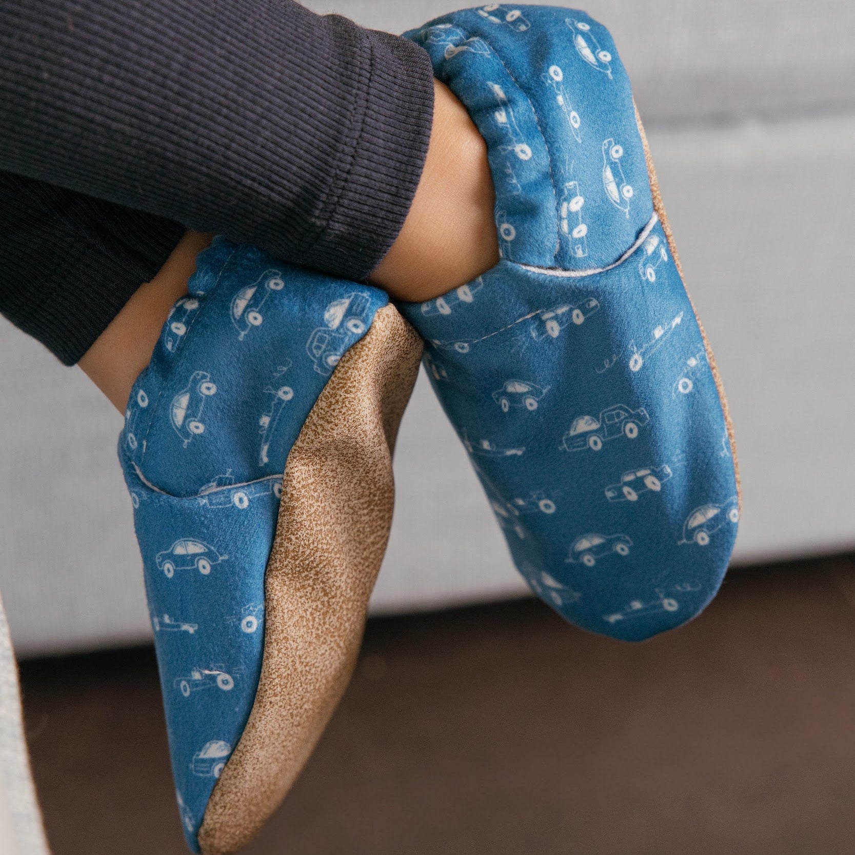 Chaussons pour bébé souples avec un motif amusant de voitures de course sur un tissu bleu marine, parfaits pour les tout-petits et les petits garçons.