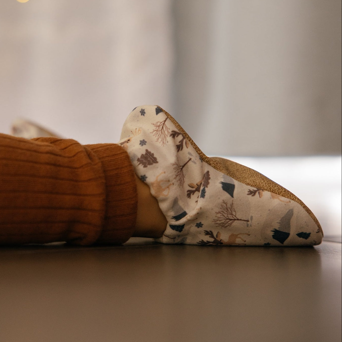 Chaussons pour bébé souples avec un motif hivernal chaleureux de rennes, flocons de neige et montagnes, parfaits pour la période des fêtes.