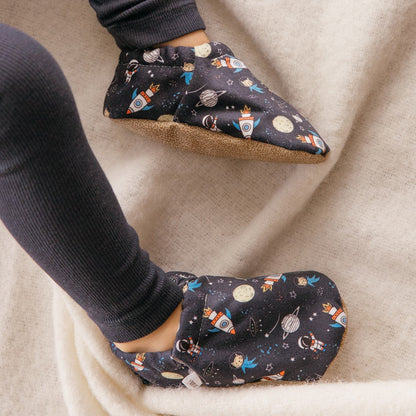 Chaussons d’intérieur pour enfant avec fusées, étoiles et planètes, portés aux pieds d’un enfant
