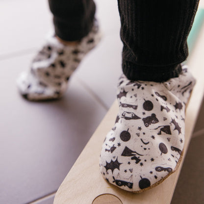 Chaussons bébé avec des animaux vêtus de costumes de super-héros sur un fond blanc.