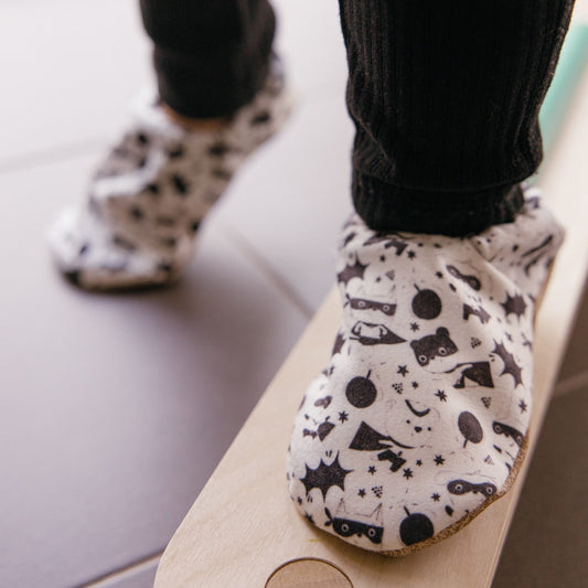Chaussons bébé avec des animaux vêtus de costumes de super-héros sur un fond blanc.