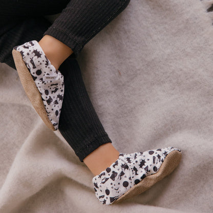 Chaussons bébé avec des animaux vêtus de costumes de super-héros sur un fond blanc.