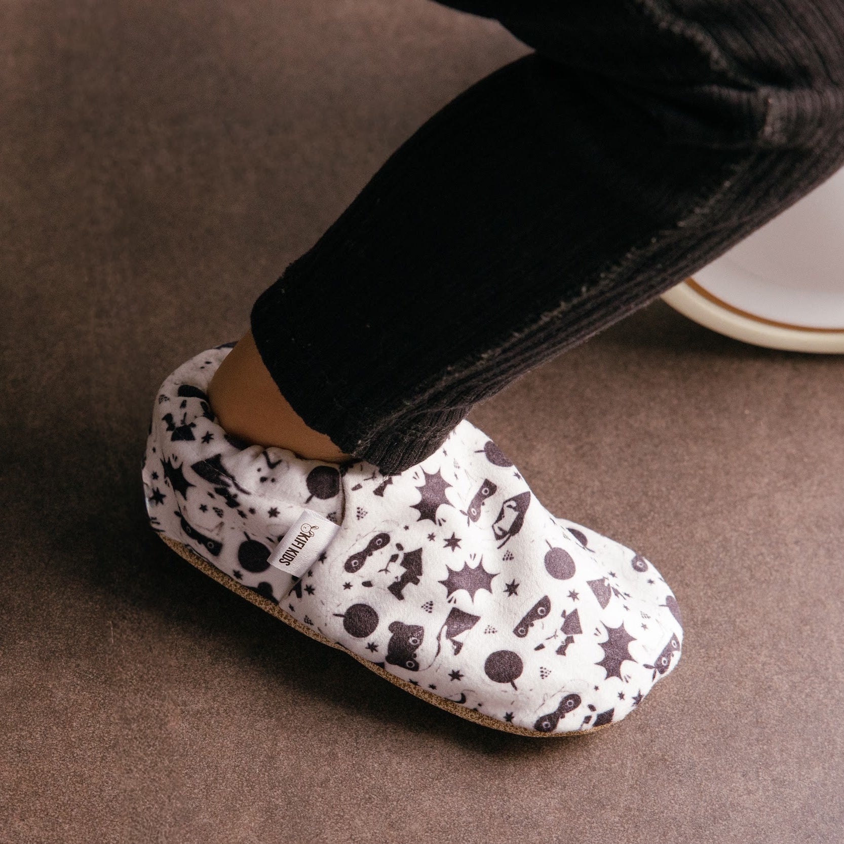 Chaussons bébé avec des animaux vêtus de costumes de super-héros sur un fond blanc.