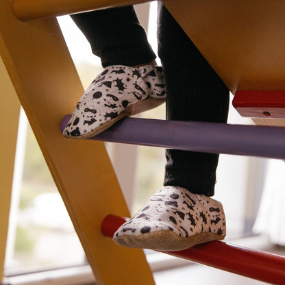 Chaussons bébé avec des animaux vêtus de costumes de super-héros sur un fond blanc.
