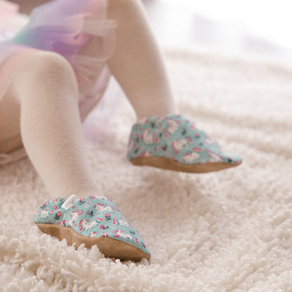Chaussons pour bébé souples avec un joli motif de licornes et de fleurs roses sur un tissu vert menthe, parfaits pour les petites filles et les tout-petits.